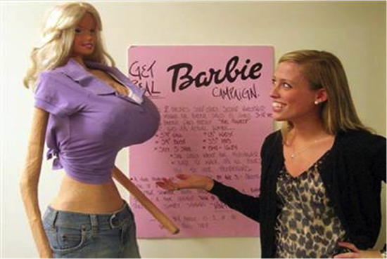 A woman standing beside a lifesize Barbie