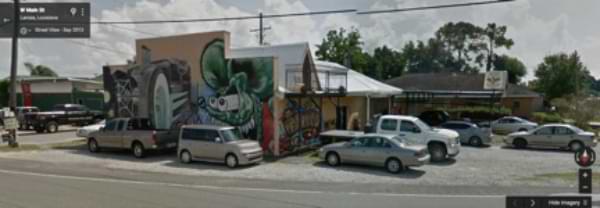 A Screen grab of Google Street view of the Southern Sting Tattoo Parlor in Larose, Louisiana. In this screen grab, the tattoo parlor is covered in random graffiti art that has no apparent political leanings.