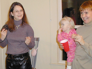 Morgan holding a baby near a woman in a skirt