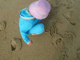 A young girl drawing in the sand