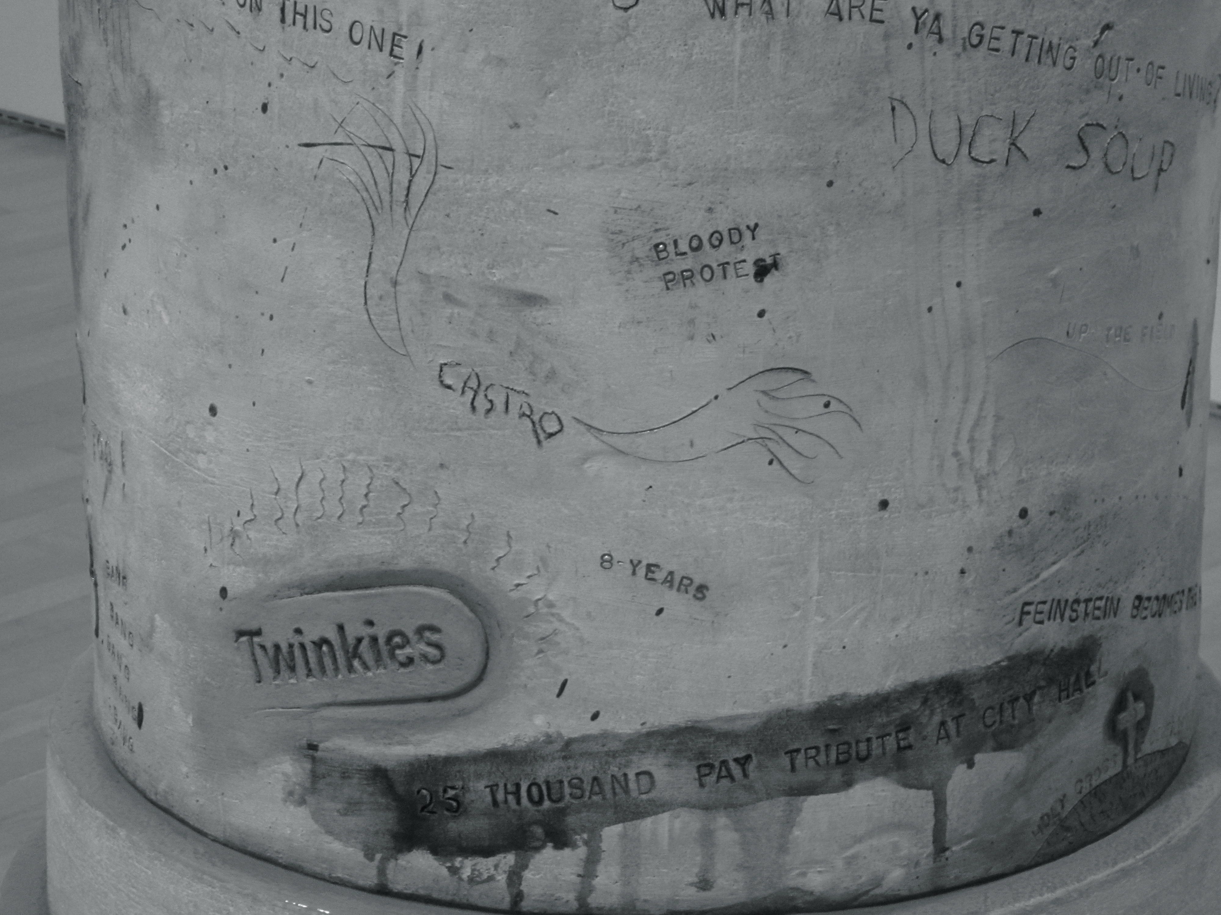 Figure 3 This is a close-up photo of the pedestal from the Moscone bust sculpture. There are rough carvings in the pedestal including words that reference the assassinations like “twinkies” and “bang, bang, bang.”