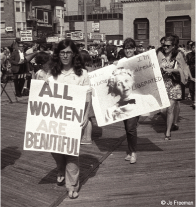 A woman carrying a sign reading 'All women are beautiful'