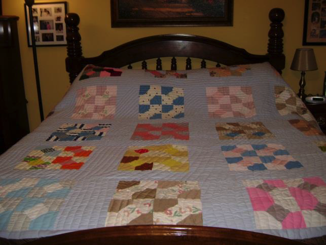 The nine-patch-style quilt MJ made for Lillie’s sister Tina, shown in her home. Quilt has light blue background with blocks featuring one bright, one light patterned fabric.
