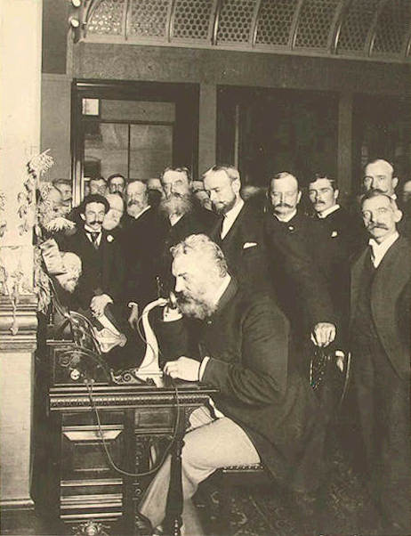 1892 photo of Alexander Graham Bell using his telephone surrounded by many men