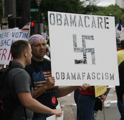 Tea Party protestors holding sign with swastika equating Obamacare to Nazi beliefs