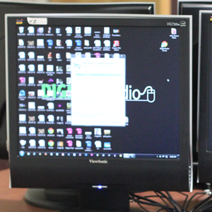 A computer monitor is on revealing a desktop full of icons representing a wide range of software available for use.
