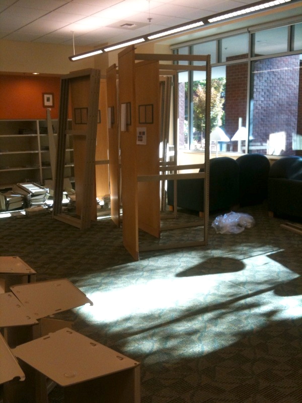 Shelves are being dismantled and sunlight is coming in through a glass wall.
