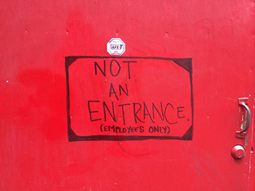 NOT AN ENTRANCE (EMPLOYEES ONLY) painted in black on a red door.