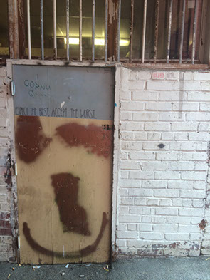 Graffiti: EXPECT THE BEST, ACCEPT THE WORST written on an abandoned door.