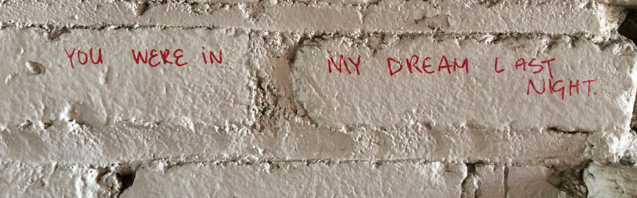 Graffiti: YOU WERE IN MY DREAM LAST NIGHT written in red on a white brick wall.