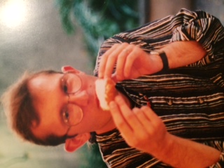 A color photograph of Jonathan, probably 27 or 28, eating a beignet in uptown New Orleans.