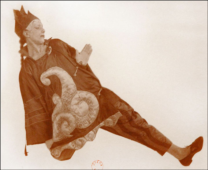 Sepia-toned photograph of dancer Léonide Massine reclining at an angle, dressed as a Chinese magician in the ballet Parade (1917). 