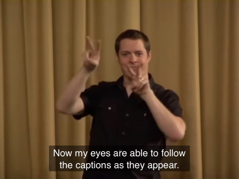 Betts demonstrates his eye gaze staying with an actor with the captions side-by -side. Captions at the bottom read, "Now my eyes are able to follow the captions as they appear."