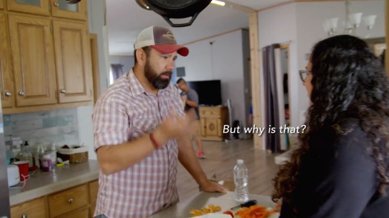 Paco and April Garcia are in their kitchen. As Paco signs, words appear in the space between the couple reading, "But why is that?"