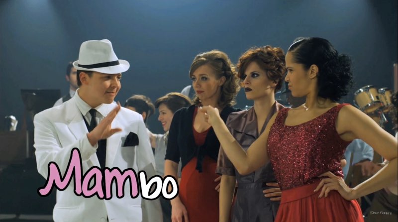 Forbes continues signing to the three women, but this time, the text states, “Mambo.” "Mam" is pink and slightly larger than the rest of the word, while “bo” is white.