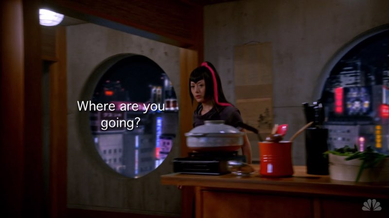 Miko, a young Japanese woman with a long pink ribbon in her hair, is walking around a desk. Open subtitles appear next to her stating, "Where are you going?"