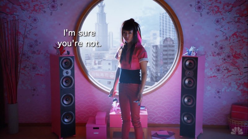 Miko is standing in a room in front of a large circular window with a city background behind her. Open subtitles next to her state, “I'm sure you’re not.”