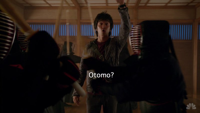 Ren is in a dojo with martial artists training in front of him, blocking his way. He calls out, reaching out with his hand as the word "Otomo?" appears in front of him.