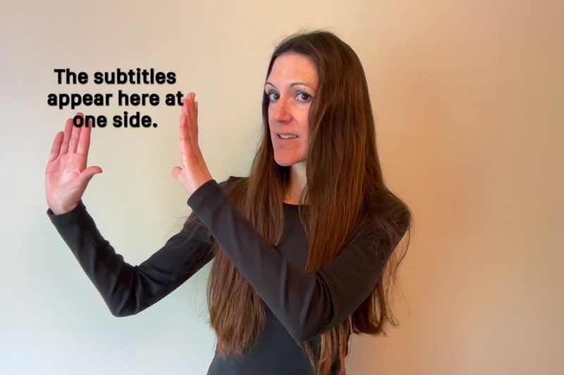 Janine Butler looks at the camera as she gestures to her left side. Subtitles appear by her left side that read "And then appear here at the other side."