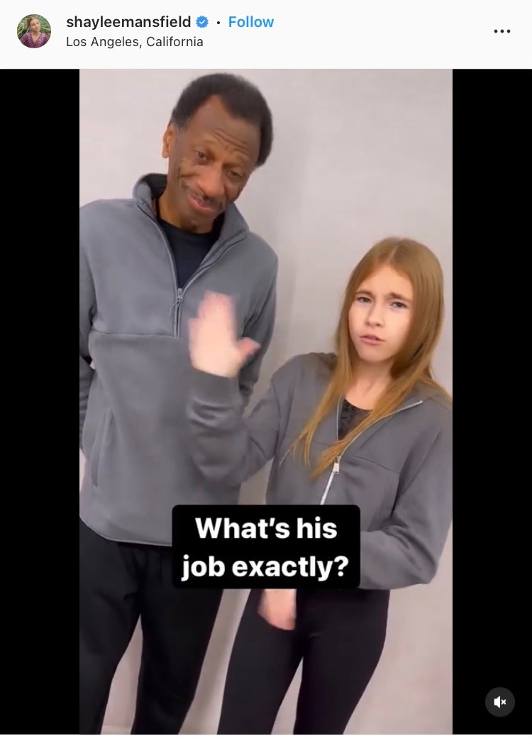 Screenshot of Shaylee Mansfield's Instagram post. Shaylee and CJ are standing next to each other. She is gesturing to CJ. Open subtitles appear in front of them and read, "What's his job exactly?"