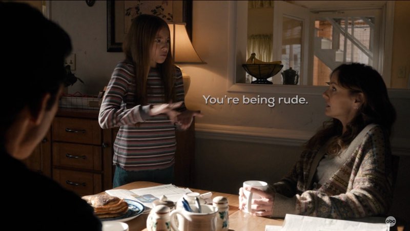Ollie is signing to the seated Birdie and Charlie in their dining room. Open subtitles appear between Ollie and Birdie that read "You're being rude."