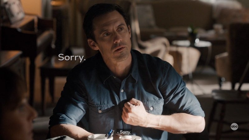 Charlie is seated at the dining table and signing “Sorry.” Open subtitles appear next to him reading, "Sorry."